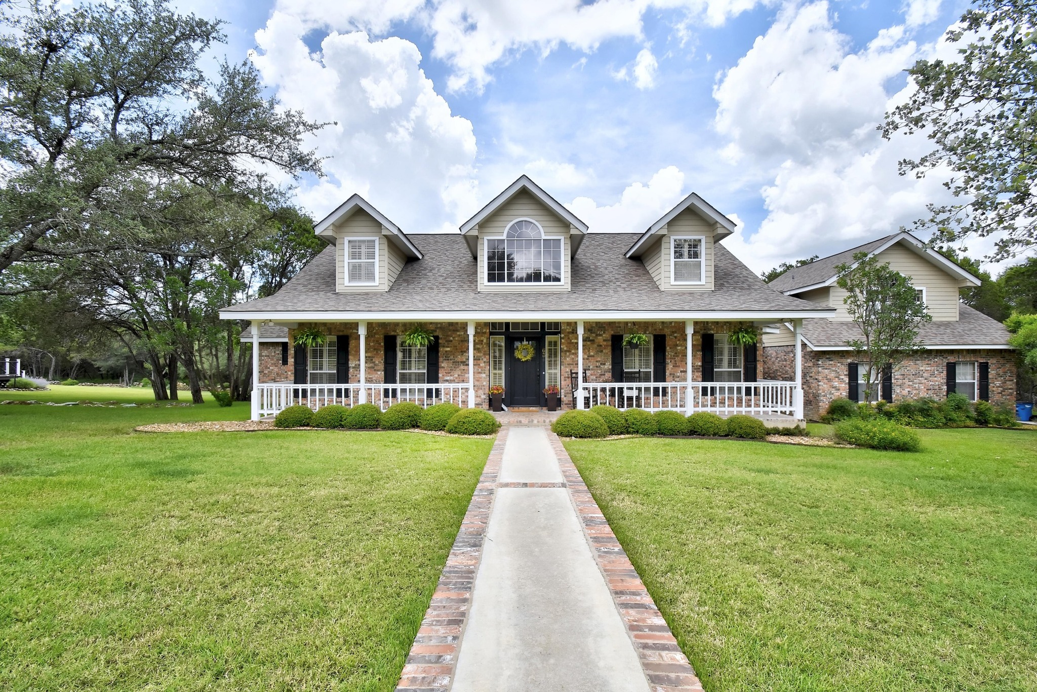 63 Hunters Point Road New Braunfels, TX 78132 - Photo 1 of 1 New england style home featuring brick siding, covered porch, and a front yard