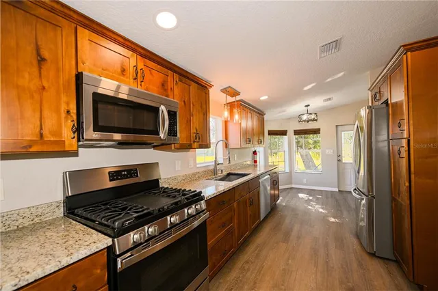 a kitchen with stainless steel appliances granite countertop a sink and a wooden cabinets