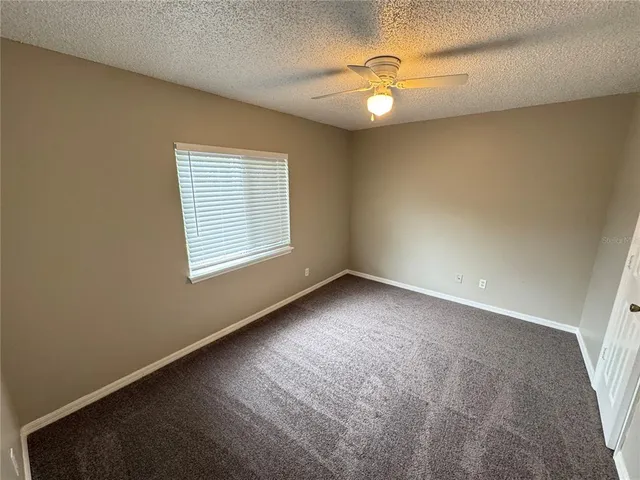 an empty room with windows and chandelier fan