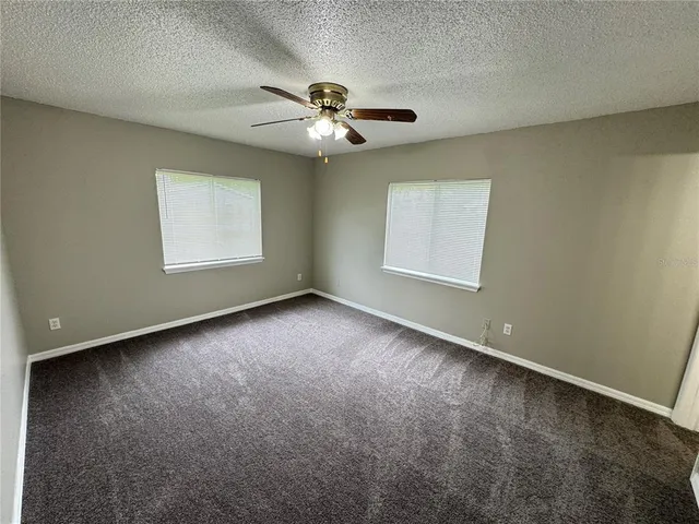 an empty room with windows and fan
