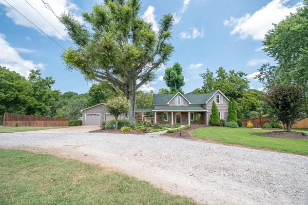 a front view of a house with a yard and trees