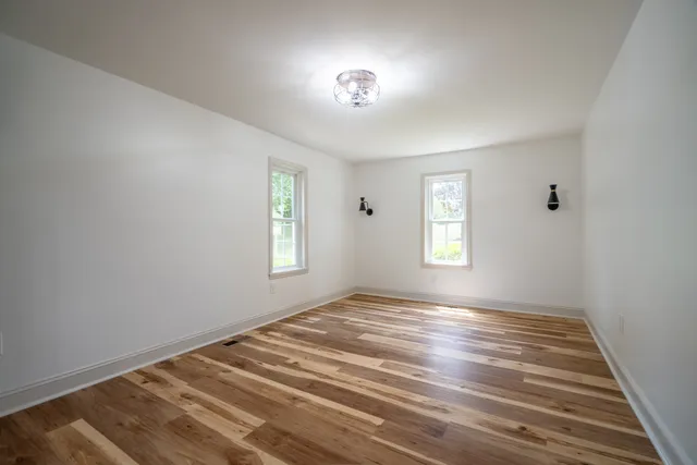 a view of a big room with wooden floor and windows