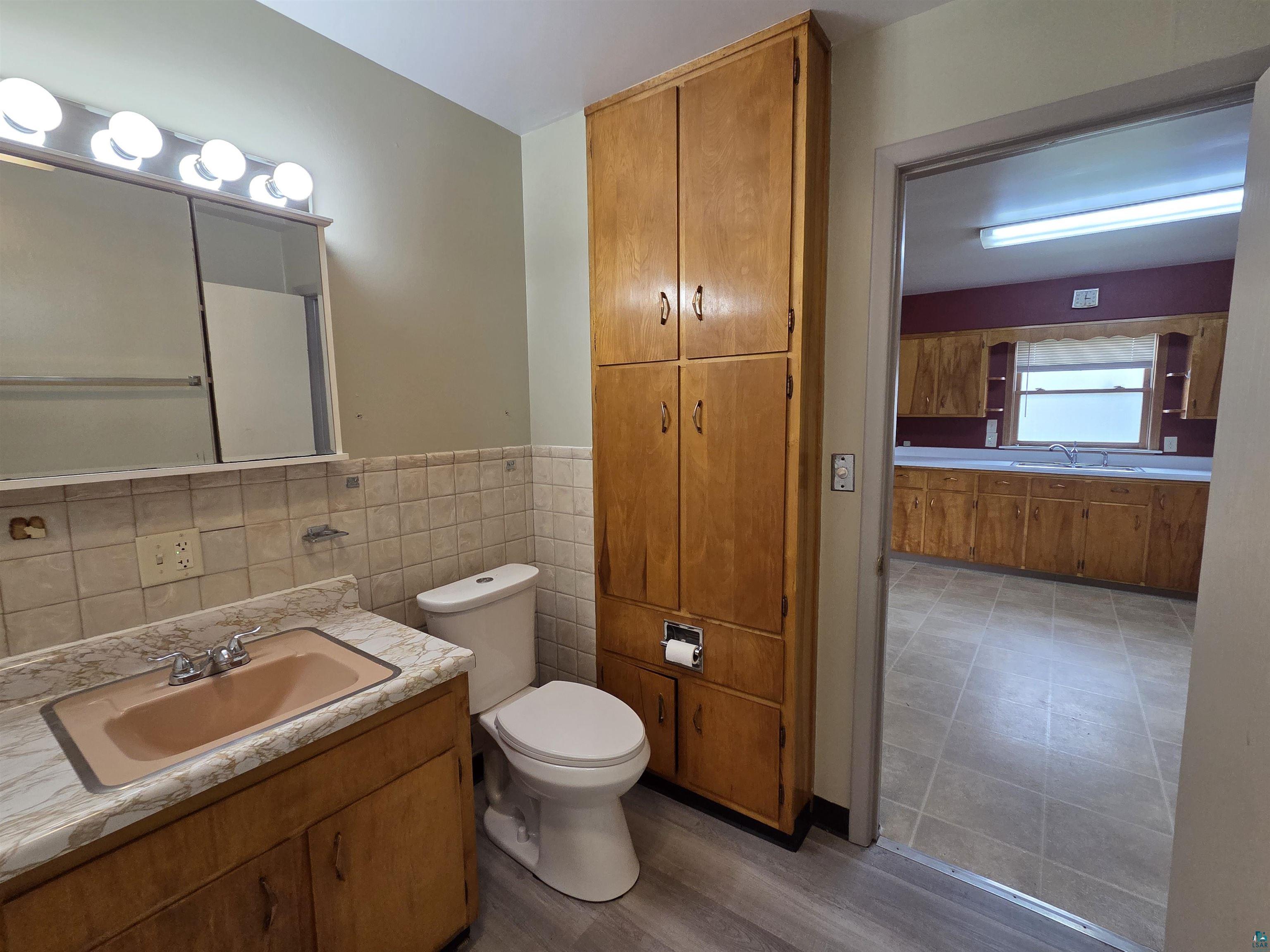 56 East 2nd Street Superior, WI 54880 - Photo 11 of 18 Bathroom featuring a vanity with an integrated sink, medicine cabinet with overhead lighting, and a floor-to-ceiling storage cabinet