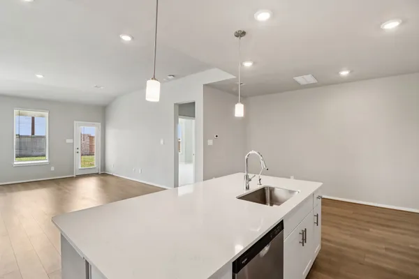 a kitchen with a sink a faucet a chandelier and wooden floor