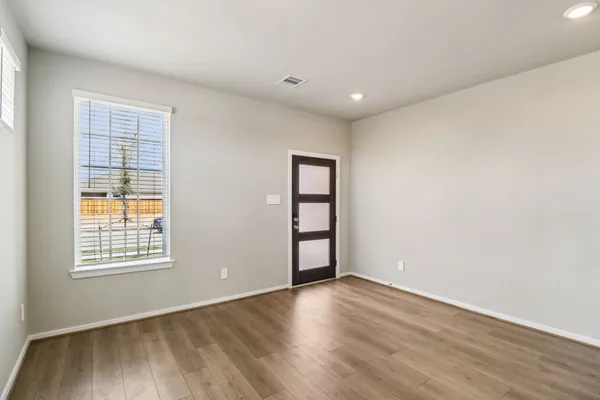 an empty room with wooden floor and windows