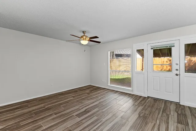 a view of an empty room with wooden floor and a window