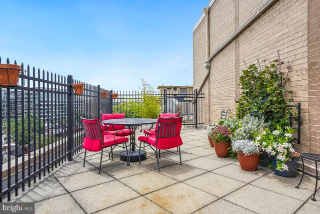 a patio with table and chairs potted plants with wooden fence