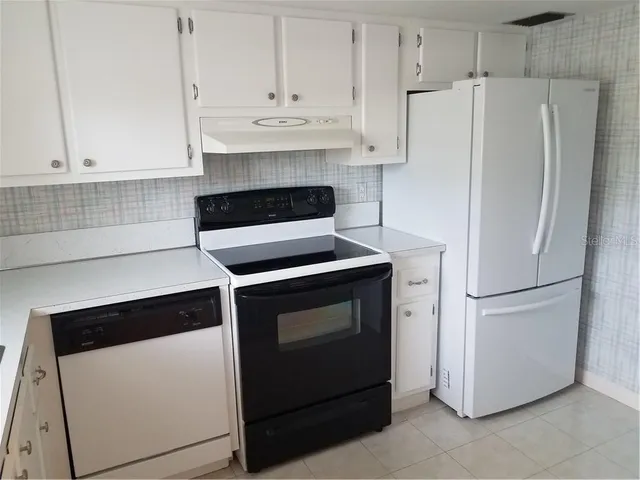 a white refrigerator freezer and a stove sitting inside of a kitchen