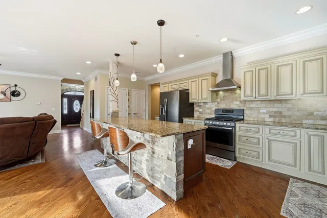 a kitchen with stainless steel appliances granite countertop a stove top oven a sink dishwasher a dining table and chairs with wooden floor