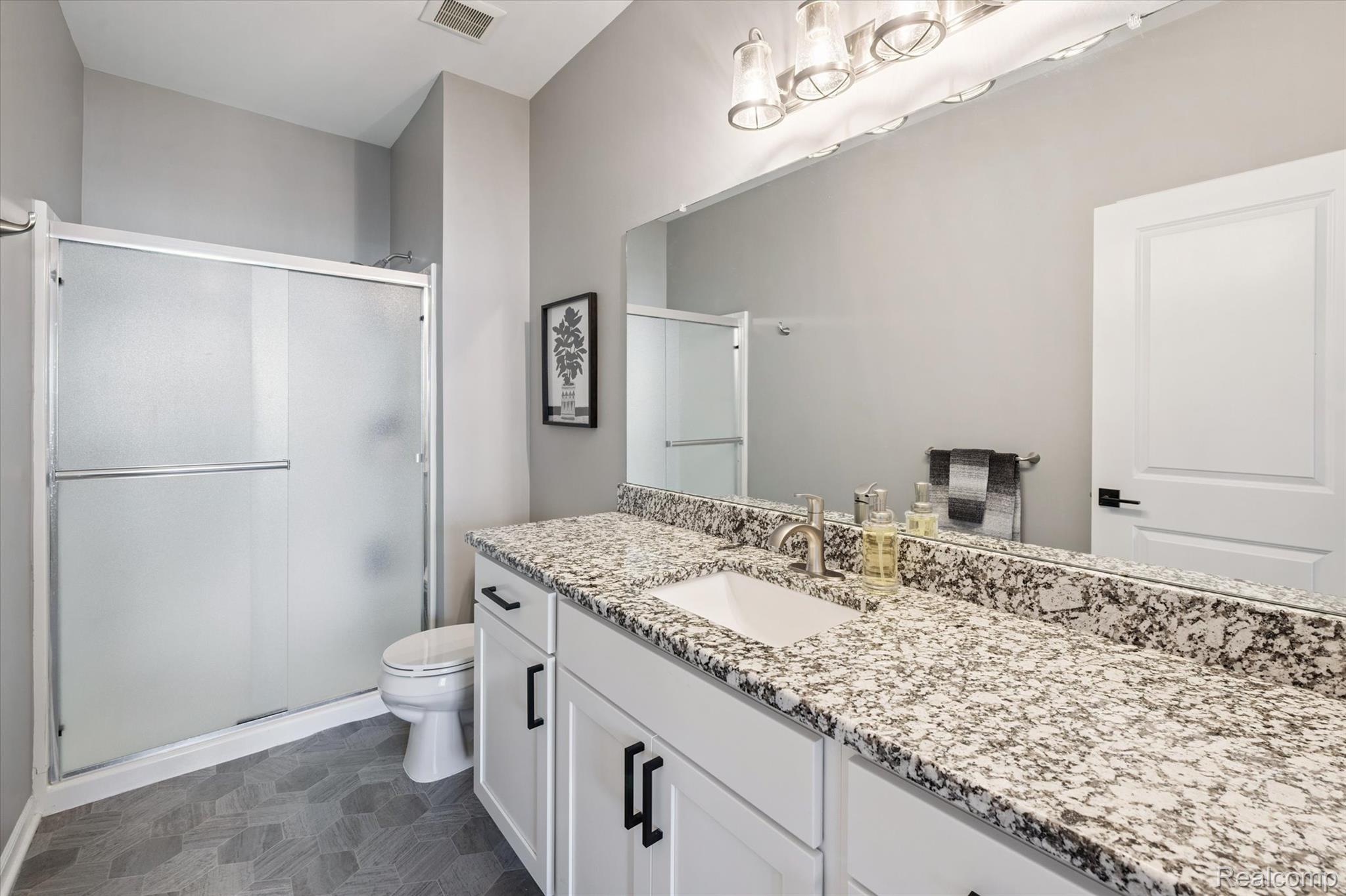9930 Ridge Run Street Howell, MI 48855 - Photo 13 of 19 Primary ensuite bath with modern honeycomb tiled floor & spacious vanity.