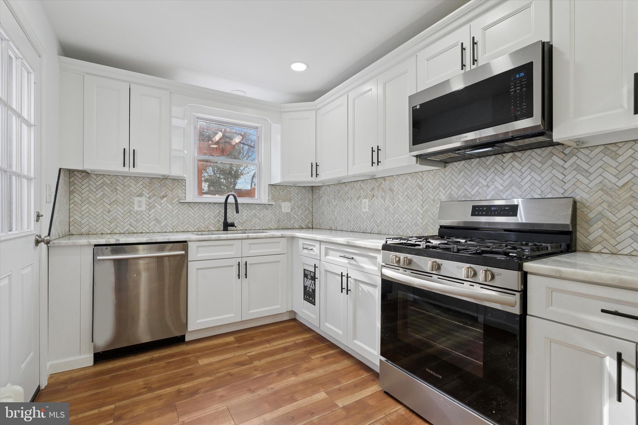 226 Upland Road Merion Station, PA 19066 - Photo 13 of 30 a kitchen with stainless steel appliances granite countertop white cabinets a sink a stove a microwave and wooden cabinets