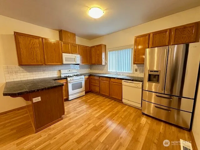 a kitchen with stainless steel appliances granite countertop a refrigerator a sink dishwasher a stove with wooden cabinets