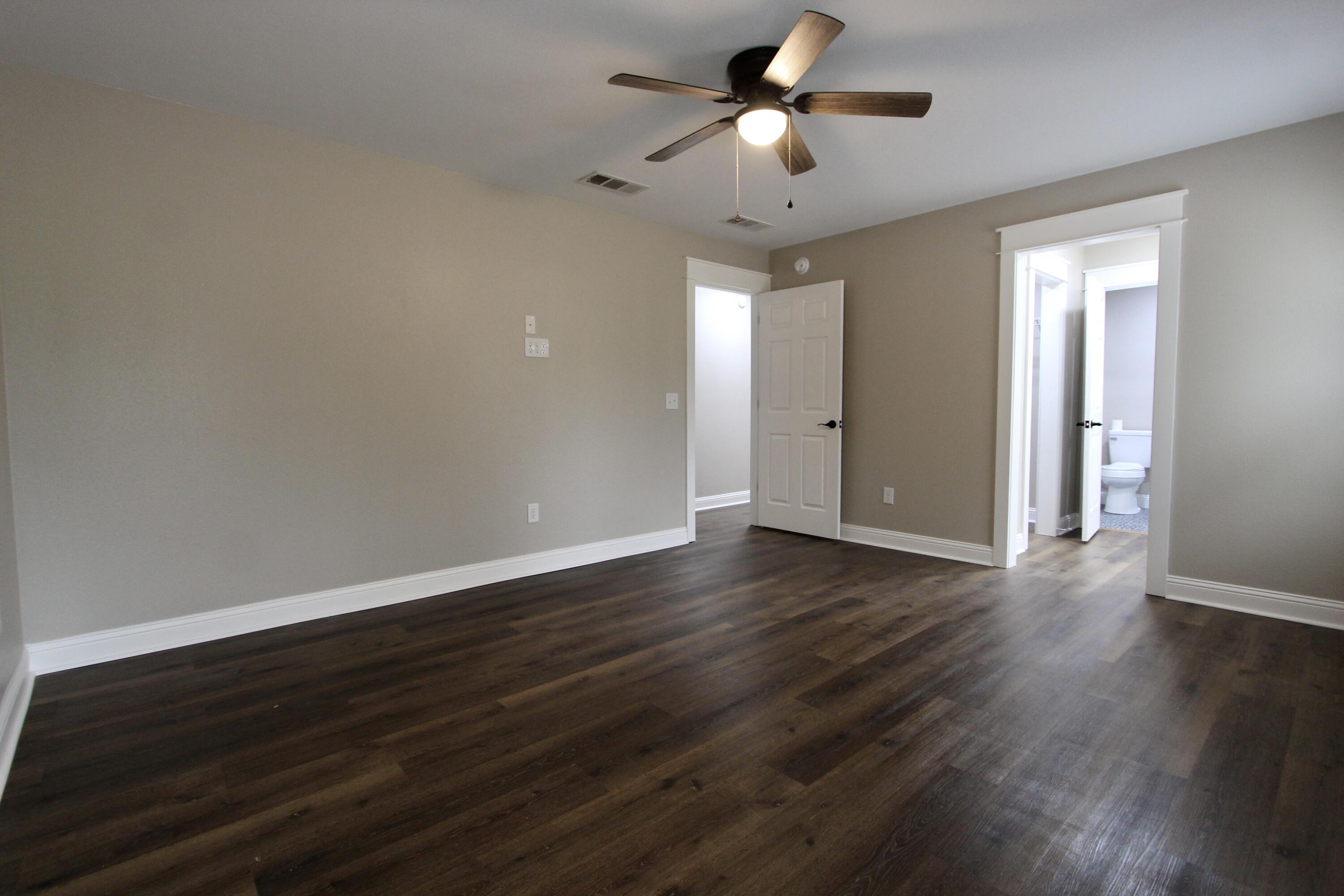 4052 Randi Road Crestview, FL 32539 - Photo 21 of 27 a view of an empty room with wooden floor and a ceiling fan