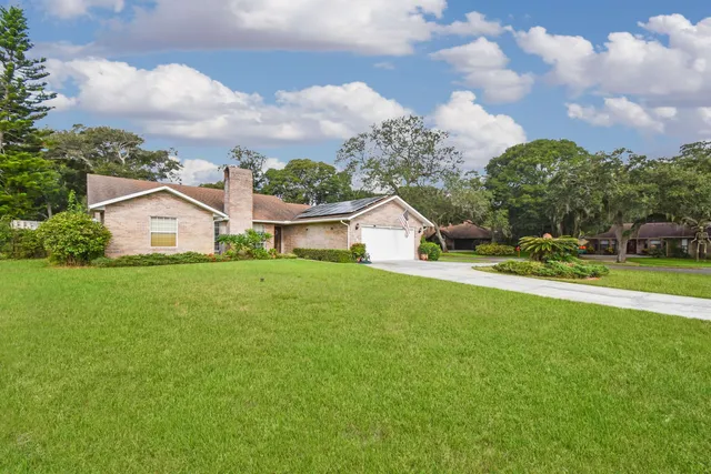 a white house with a big yard and large trees