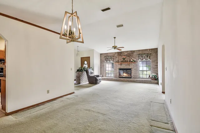 a view of an empty room with a fireplace and chandelier