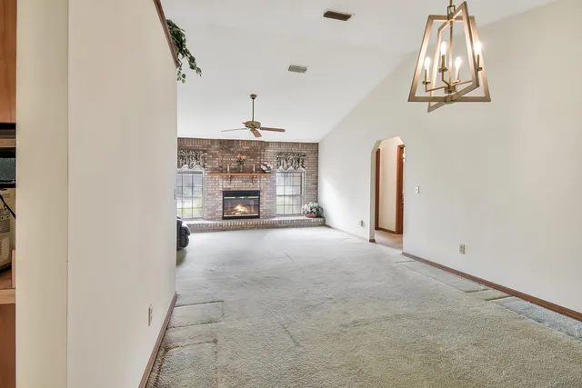 an empty room with a fireplace and chandelier