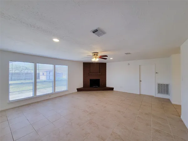 an empty room with windows and fireplace