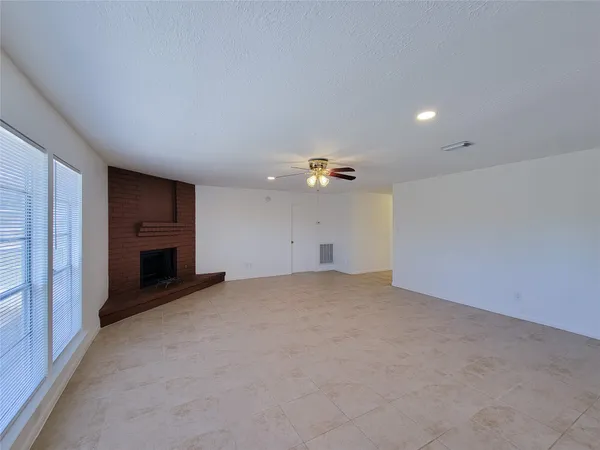 an empty room with a fireplace and natural light