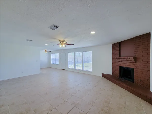 an empty room with windows and fireplace