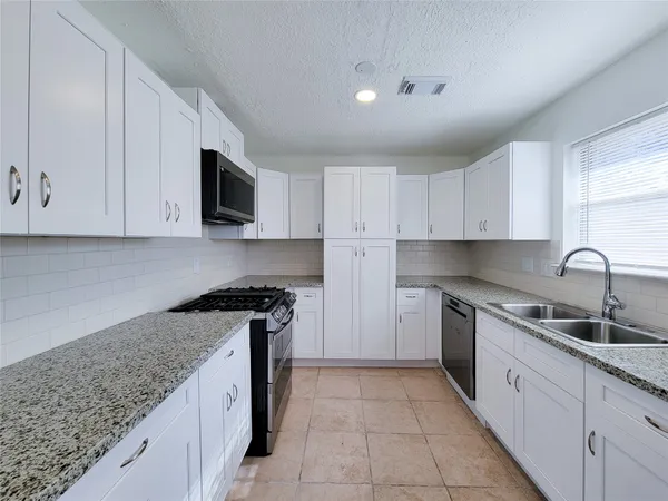 a kitchen with stainless steel appliances granite countertop a sink and a stove