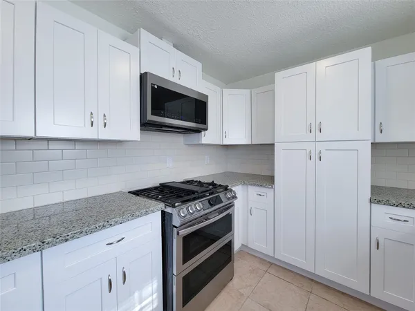 a kitchen with granite countertop white cabinets and stainless steel appliances