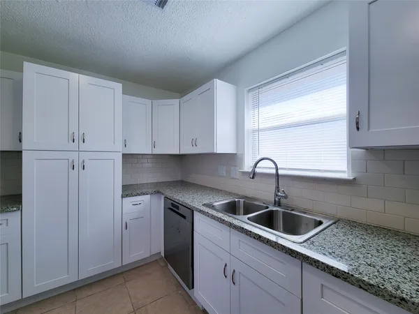 a kitchen with white cabinets sink and dishwasher