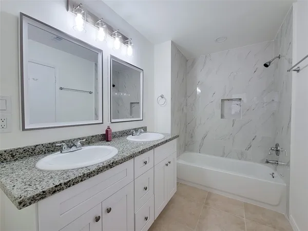 a bathroom with a granite countertop sink and a mirror a bathtub