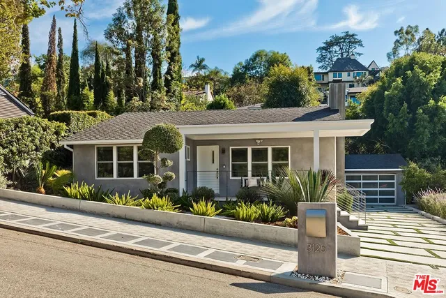 a front view of a house with a garden and plants