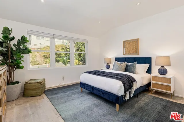a spacious bedroom with a bed and a potted plant