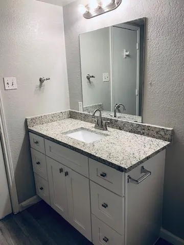 a bathroom with a granite countertop sink and a mirror
