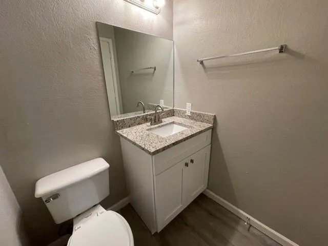 a bathroom with a granite countertop toilet sink and mirror