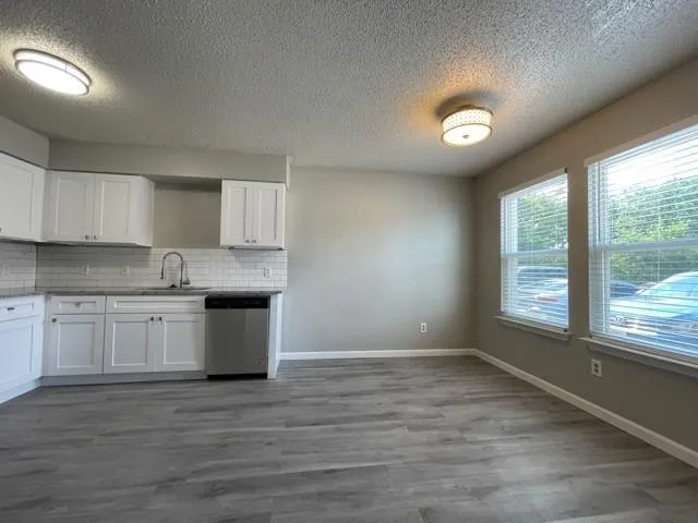 a kitchen with granite countertop white cabinets and wooden floor