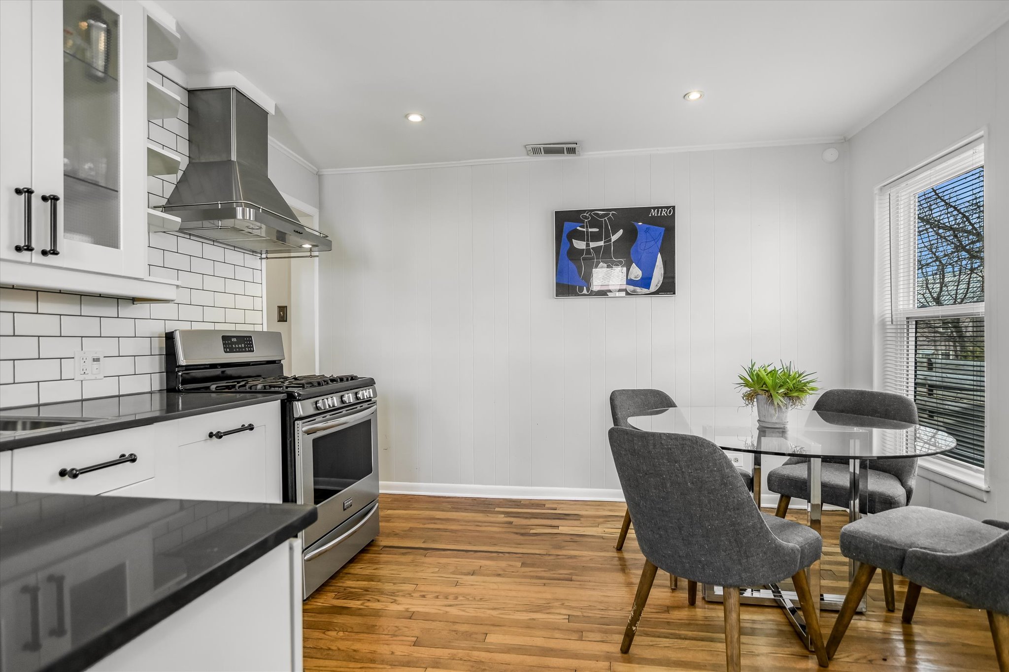 604 East 46th Street Austin, TX 78751 - Photo 7 of 16 a kitchen with stainless steel appliances granite countertop a white stove top oven a dining table and chairs with wooden floor