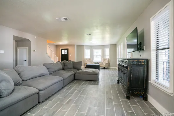 a living room with furniture a flat screen tv and a window