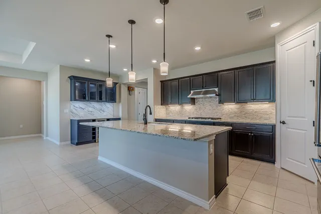 a large kitchen with granite countertop a stove a sink a refrigerator and a wooden cabinets