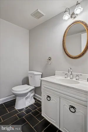 a bathroom with a granite countertop toilet a sink and a mirror