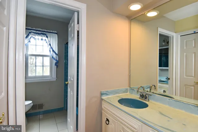 a bathroom with a granite countertop sink toilet and mirror