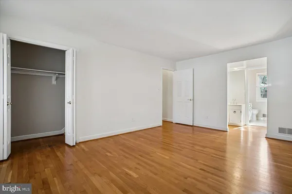 an empty room with wooden floor & windows