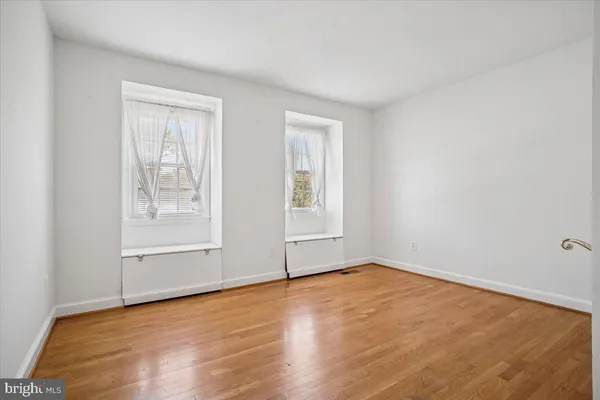an empty room with wooden floor and windows
