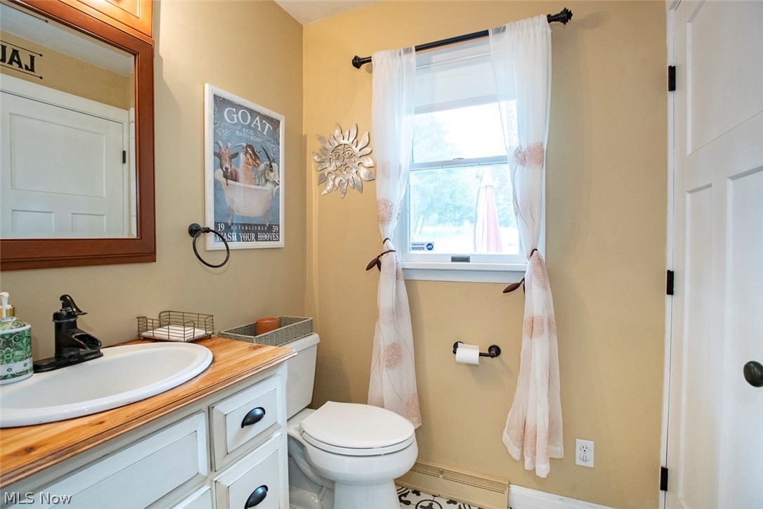 3090 Sourek Road Akron, OH 44333 - Photo 17 of 36 Bathroom featuring a window, white vanity with wood-finish countertop, undermount sink, and black faucet