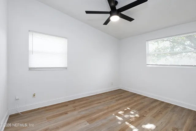 an empty room with wooden floor and windows