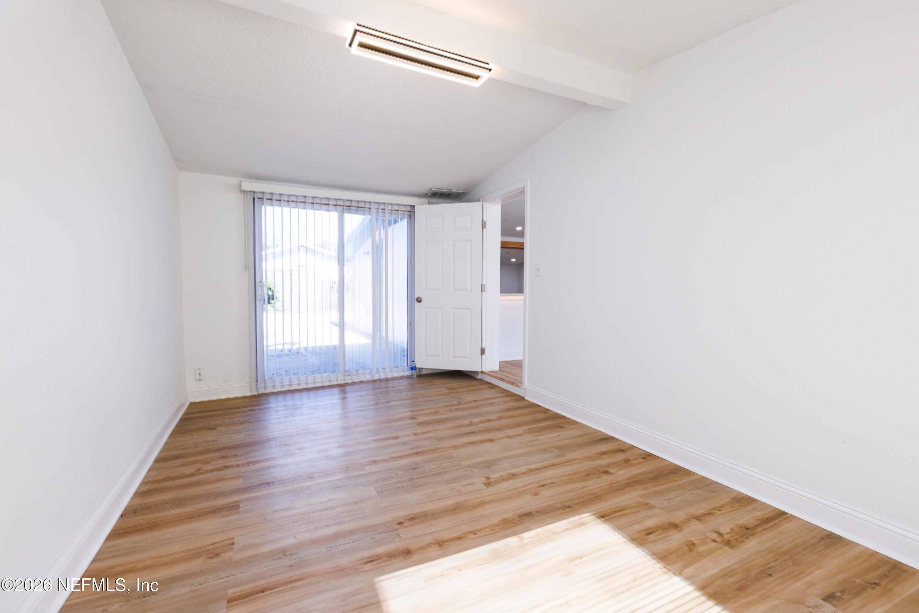203 Rio Road Jacksonville, FL 32218 - Photo 17 of 24 a view of an empty room with wooden floor and a window