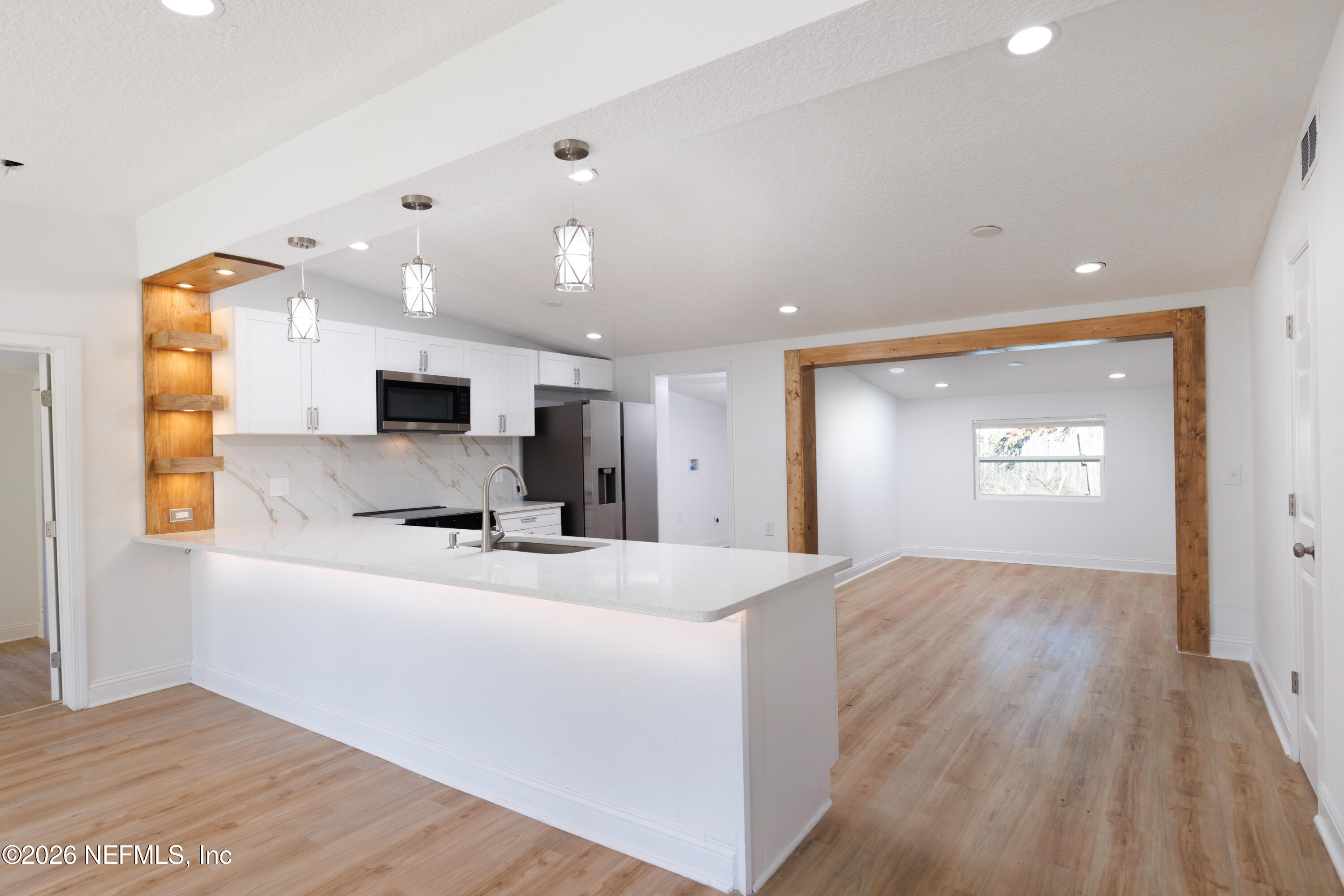203 Rio Road Jacksonville, FL 32218 - Photo 4 of 24 a large white kitchen with kitchen island a sink wooden floor and a refrigerator