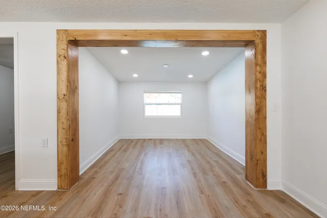 an empty room with wooden floor cabinet and windows
