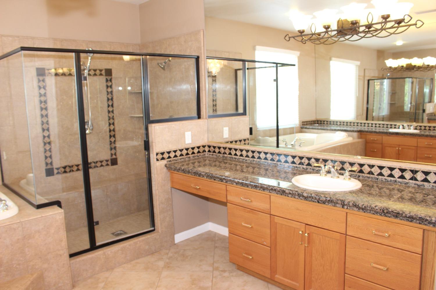 2478 Rall Avenue Clovis, CA 93611 - Photo 23 of 35 a bathroom with a granite countertop sink a mirror and a bathtub