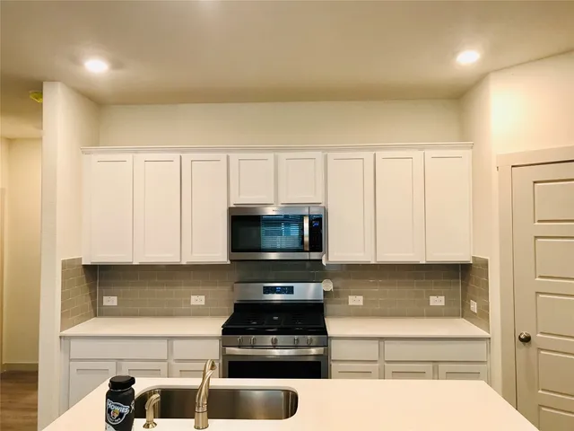 a kitchen with white cabinets and black appliances