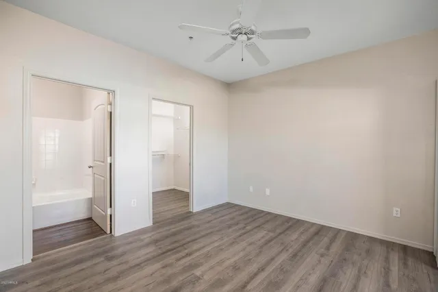 an empty room with wooden floor and a ceiling fan