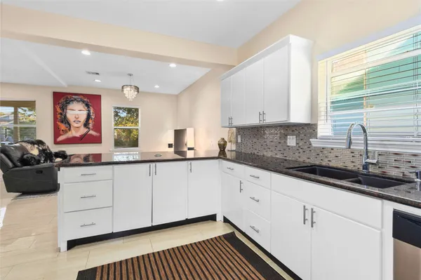 a kitchen with granite countertop white cabinets sink and window