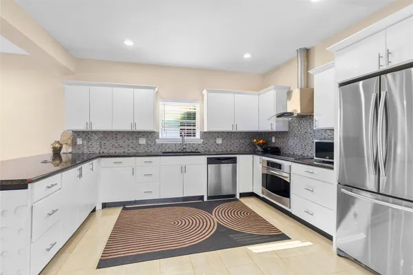 a kitchen with granite countertop a sink stainless steel appliances and cabinets