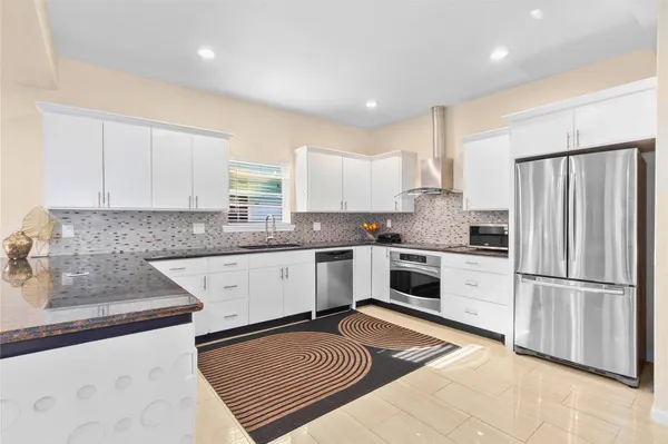 a kitchen with granite countertop a refrigerator oven a sink and cabinets